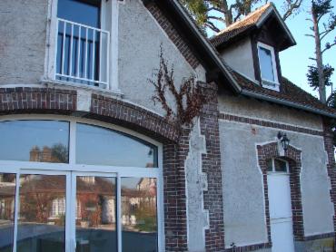 Façade en brique et pierre de la maison, grande baie vitrée cintrée au rez-de-chaussée