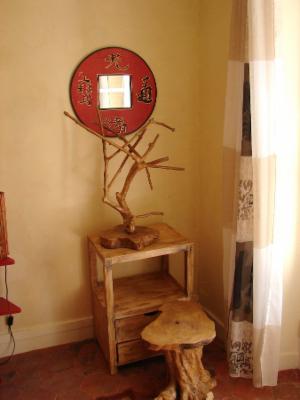 Console en bois brut surmontée d'un miroir rond à cadre rouge et calligraphies, branche décorative